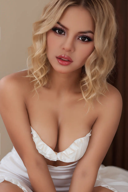 Solenne doll leaning forward in a white dress with short blonde waves framing her face