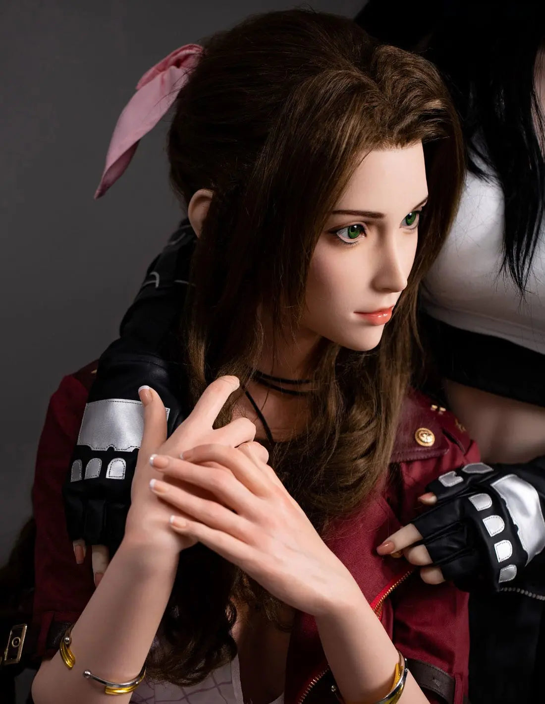 Hera, iconic green eyes, dark brown long curls hair, dark red suede jacket, white V-neck slip dress, pink bow, black choker, grey studio lighting background, sitting and leaning in someone's arms– European bookish bombshell companion sex doll by TopLovedoll