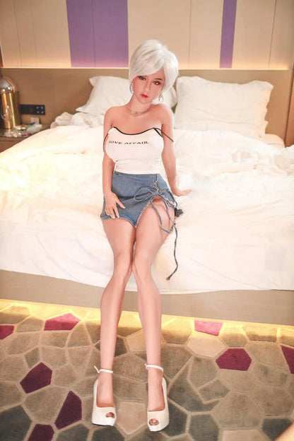 Anahi short platinum blonde hair tan skin white fitted tank denim micro skirt bold Shibuya street style pose, sitting on the hotel bed, The straps of her slip tank fallen to the arms, the knot on her mini skirt untied– Asian blonde pornstar sex doll by TopLoveDoll