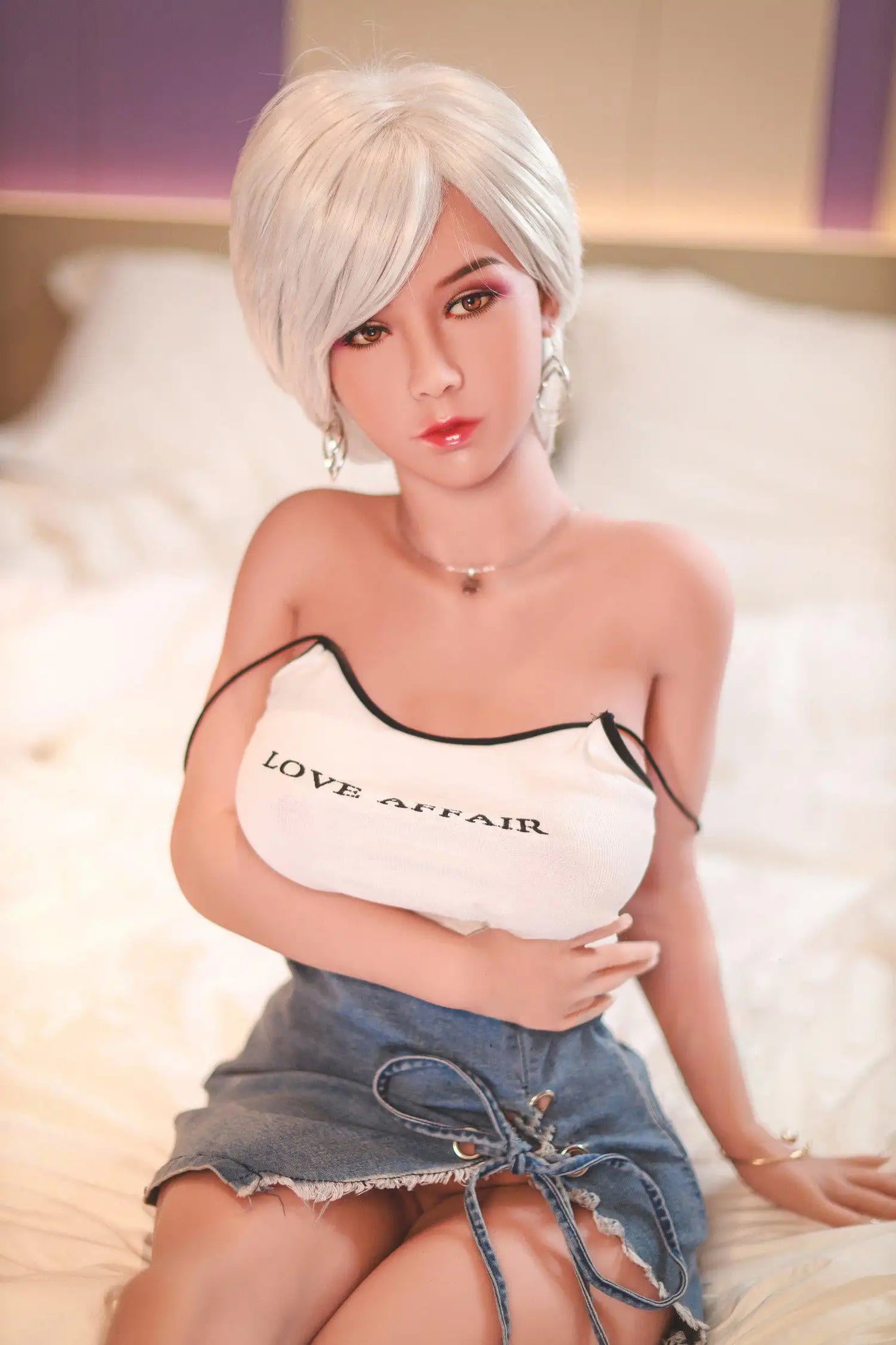 Anahi short platinum blonde hair tan skin white fitted tank denim micro skirt bold Shibuya street style pose, w-sitting on the hotel bed, The straps of her slip tank fallen to the arms, the knot on her mini skirt untied, silver hoop earrings– Asian blonde pornstar sex doll by TopLoveDoll