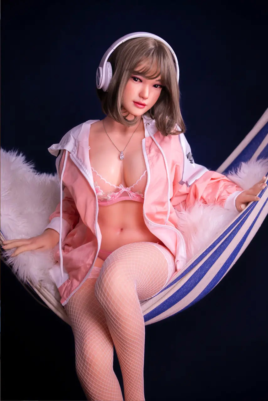 Antonella flaxen bob pear-cut J-style sweet girl in pink tracksuit and blush lace lingerie lounging on blue-white striped hammock with over-ear headphones, sitting on the hammock – curvy Asian sex doll by TopLoveDoll