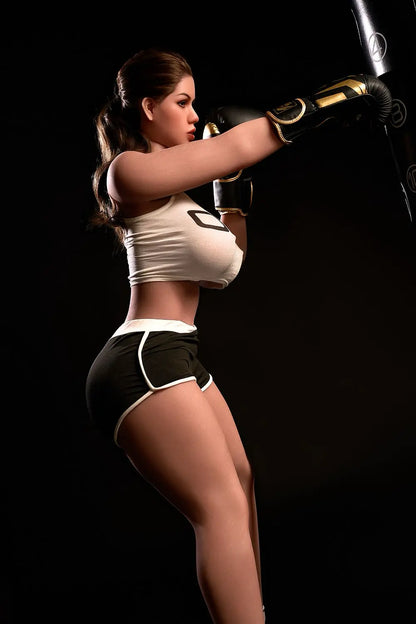 Sporty Nori bbw sex doll seated in gym with boxing gloves, white crop top, brunette hair, huge breasts, customizable sex robot doll by TopLoveDoll