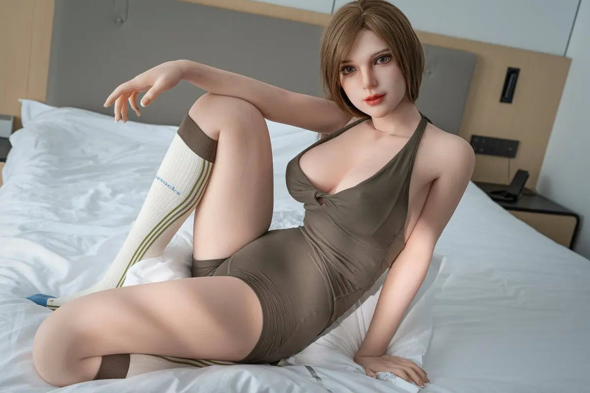 Gadora pretty sex doll reclining on a white bed in an olive romper, with one knee raised