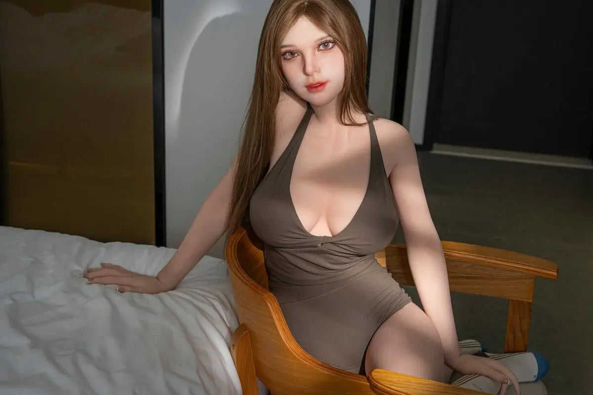Gadora beautiful brunette doll seated beside a bed, with long brown hair and an olive halter romper