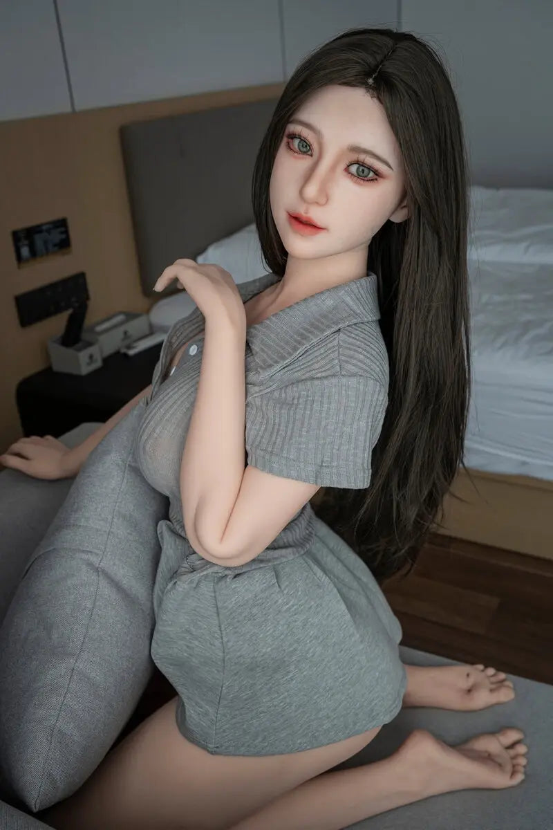 Gal pretty girl next door sex doll kneeling on a gray sofa in a gray collared dress, with long dark hair