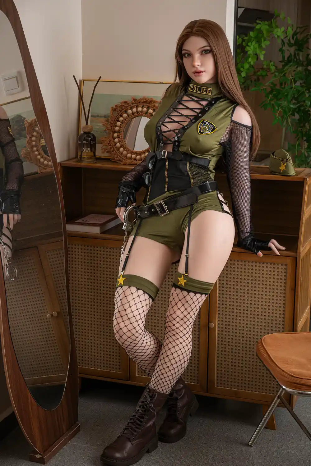 Officer Vera European sex doll standing beside a wooden cabinet with crossed ankles, wearing an olive lace-up costume and police patches.