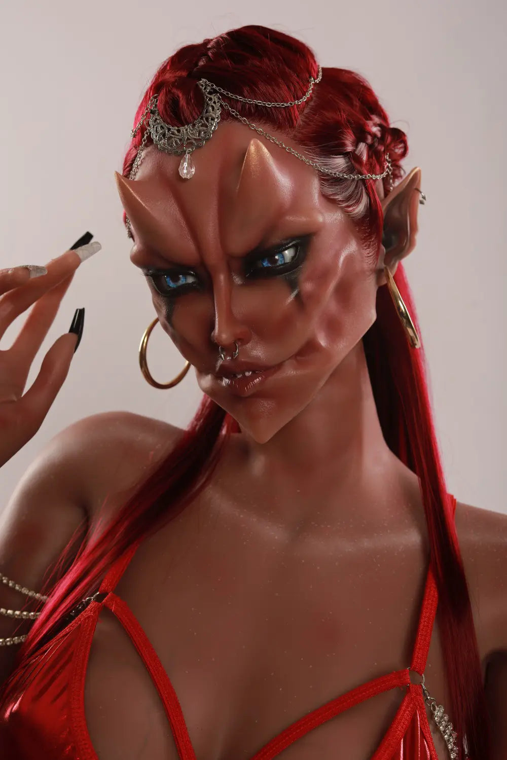 Close-up of Veyra sex doll's sculpted fantasy face with red hair, a silver headpiece and one hand beside the temple
