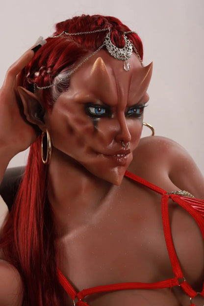 Closer seated view of Veyra sex doll with one hand beside the head, a red top and beaded mesh skirt