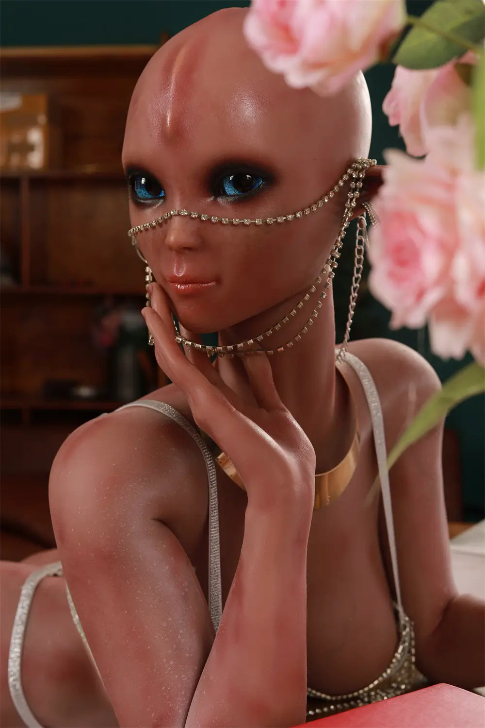 Close-up of Vaelis alien face framed by pink roses, showing blue eyes and decorative chains