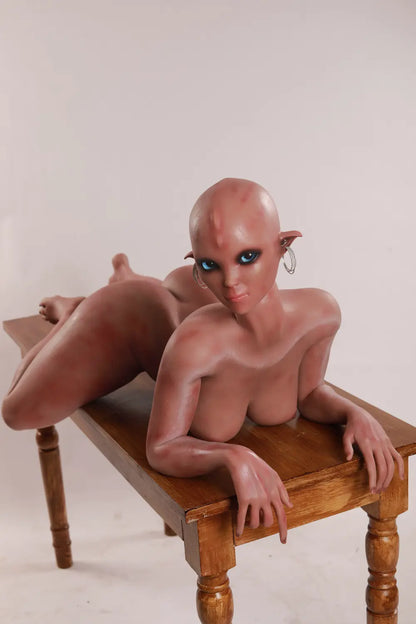High-angle front view of Vaelis sex doll lying on a wooden table with bent legs