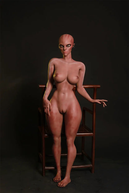 Full-length front view of unclothed Nyxie alien sex doll standing in front of a wooden chair