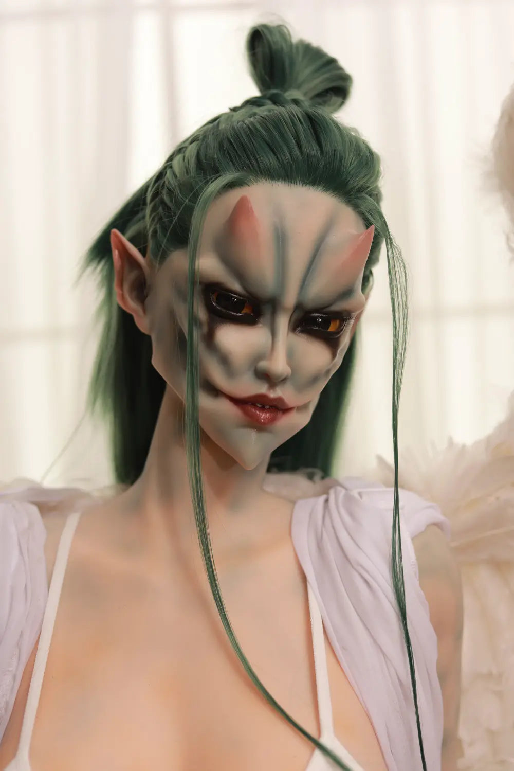 Close-up of Morveth's gray-toned fantasy face with dark eye markings and green hair tied in a topknot