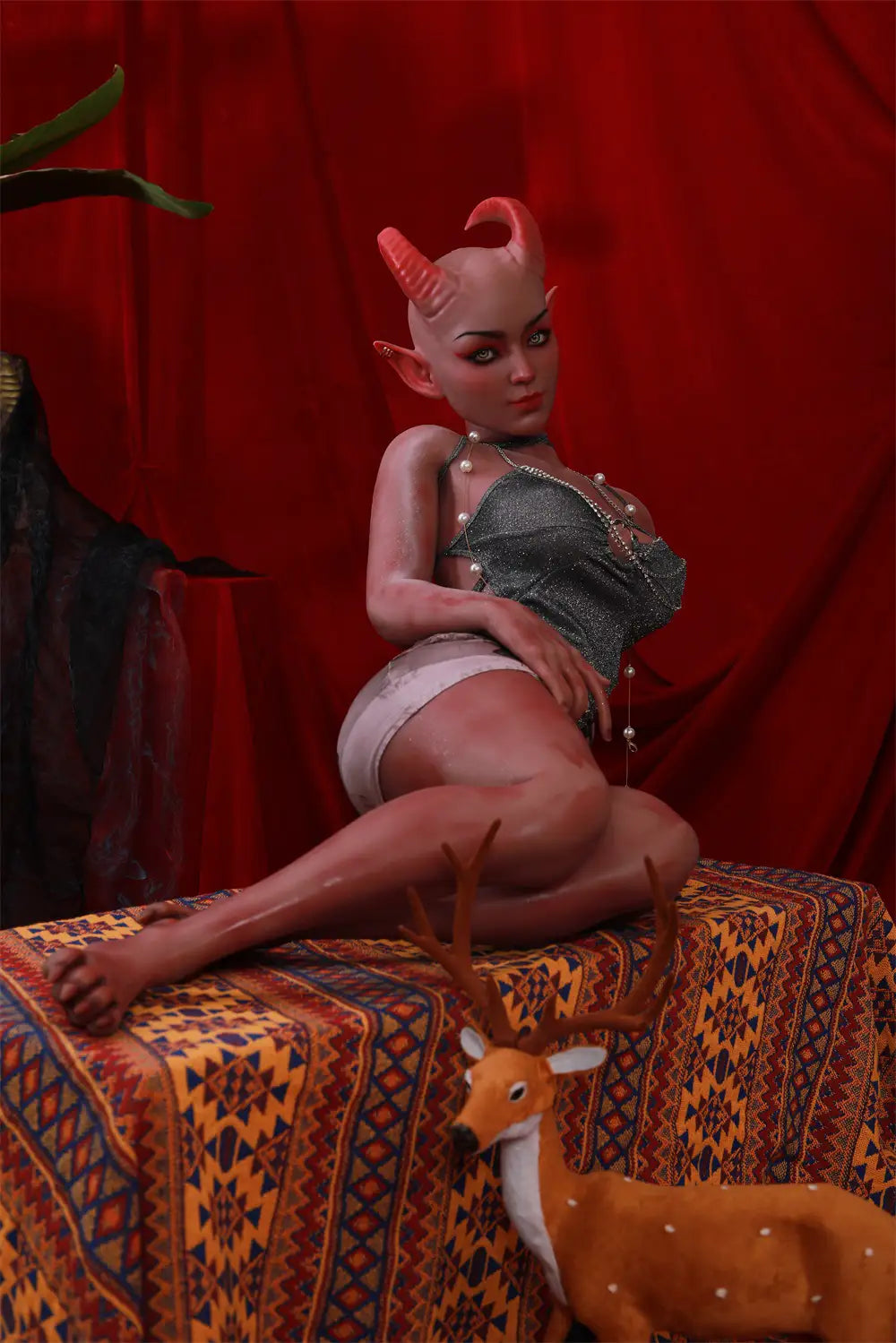 Side view of Tauris sex doll seated with legs extending across a patterned platform