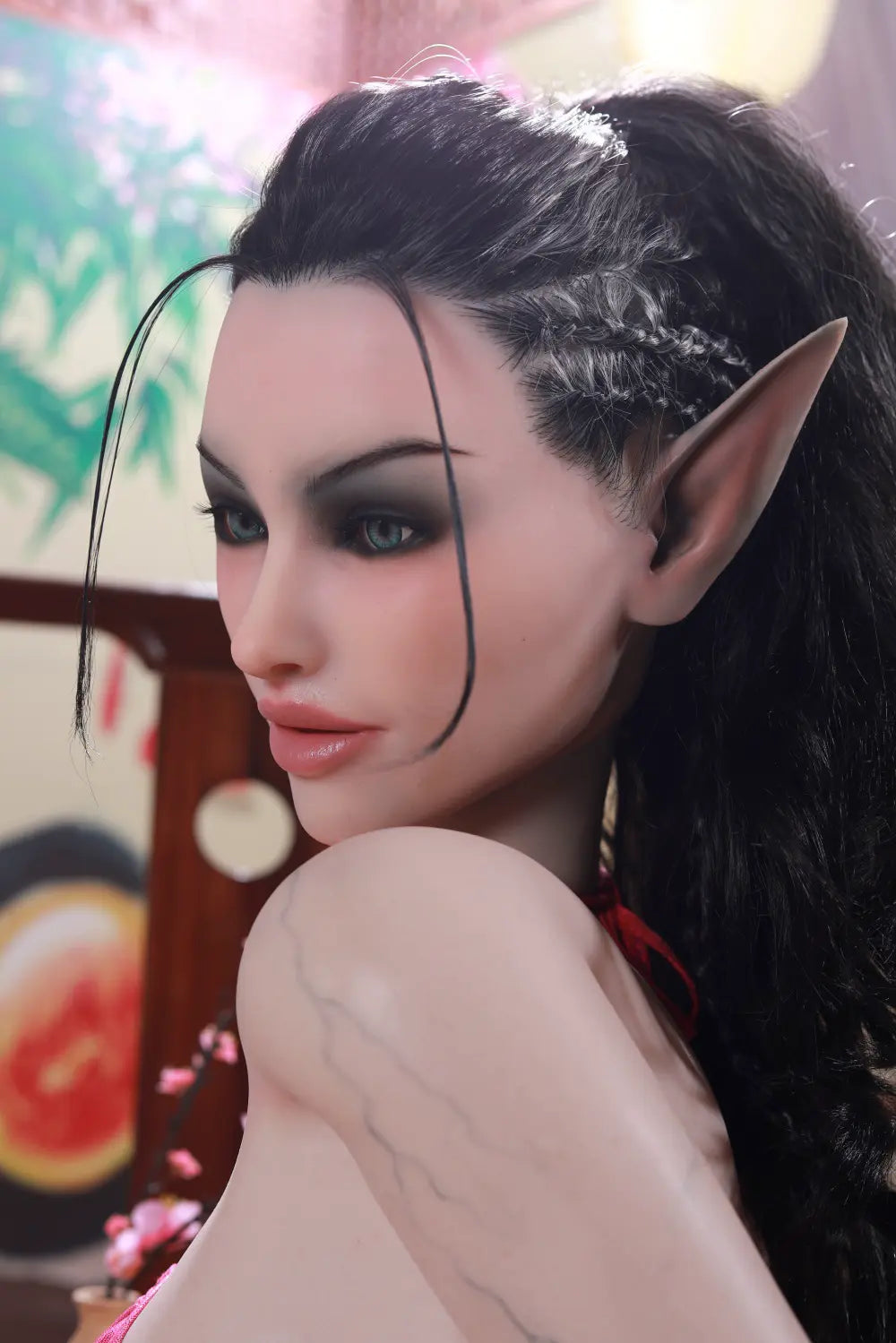 Side view of Sylthra sex doll seated with dark hair falling along the back