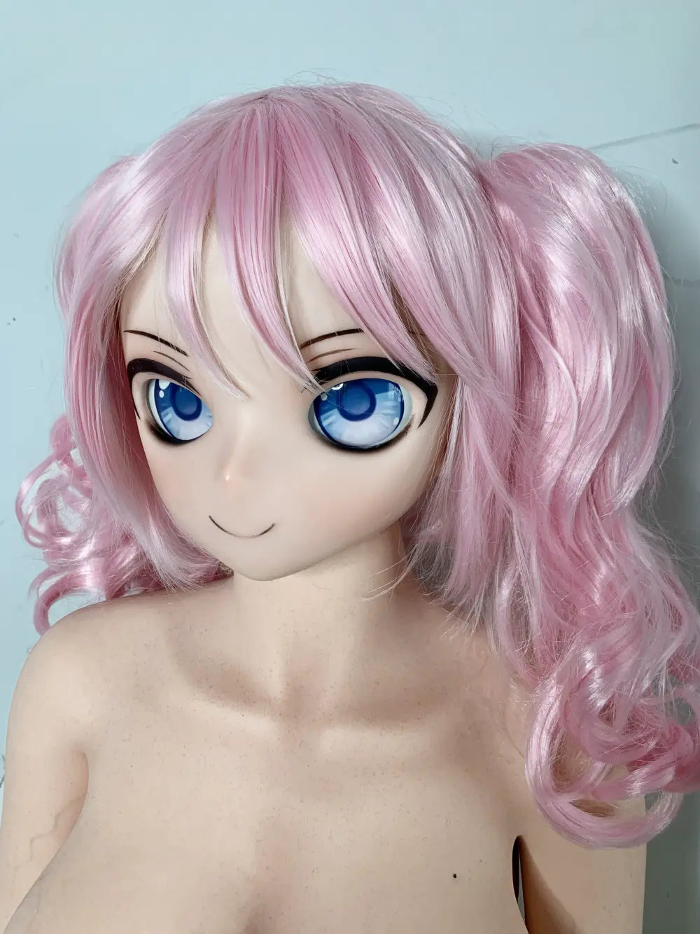 Factory close-up of Mirumi's 2D-style anime face with blue eyes and pink bangs
