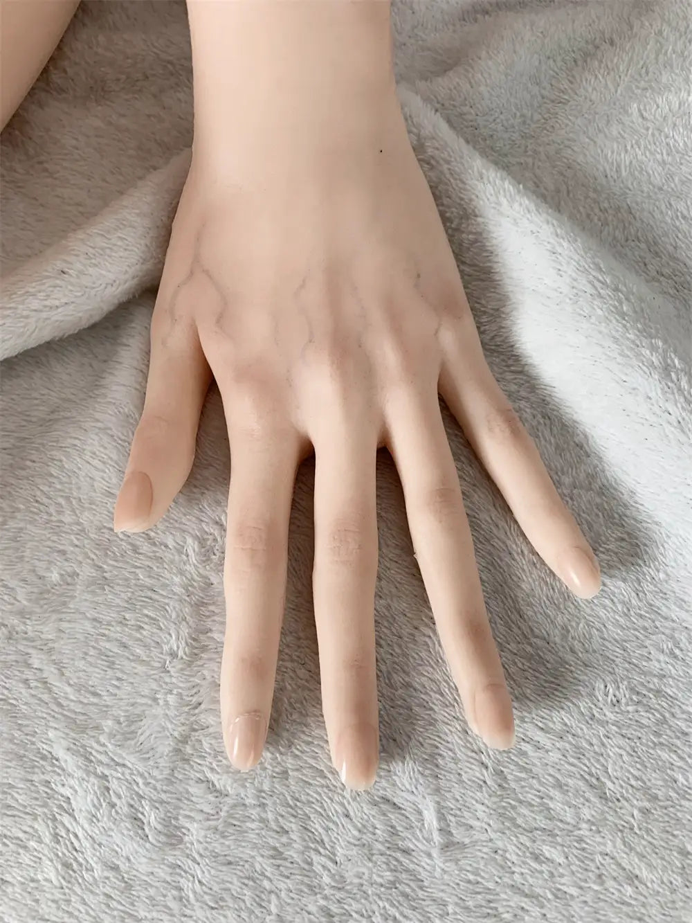 Factory detail photo of Mirumi sex doll's hand resting on a white textured surface