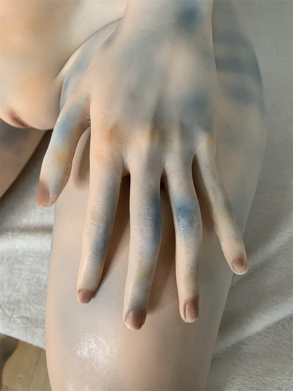 Factory detail photo of Sylvara sex doll's hand resting on the thigh, showing sculpted fingers and nails