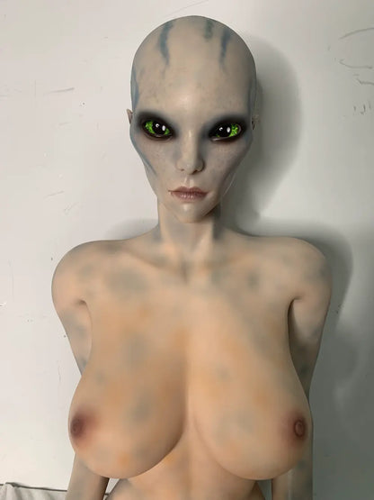 Opposite three-quarter factory reference view of Aelyth sex doll with hands resting on the thighs