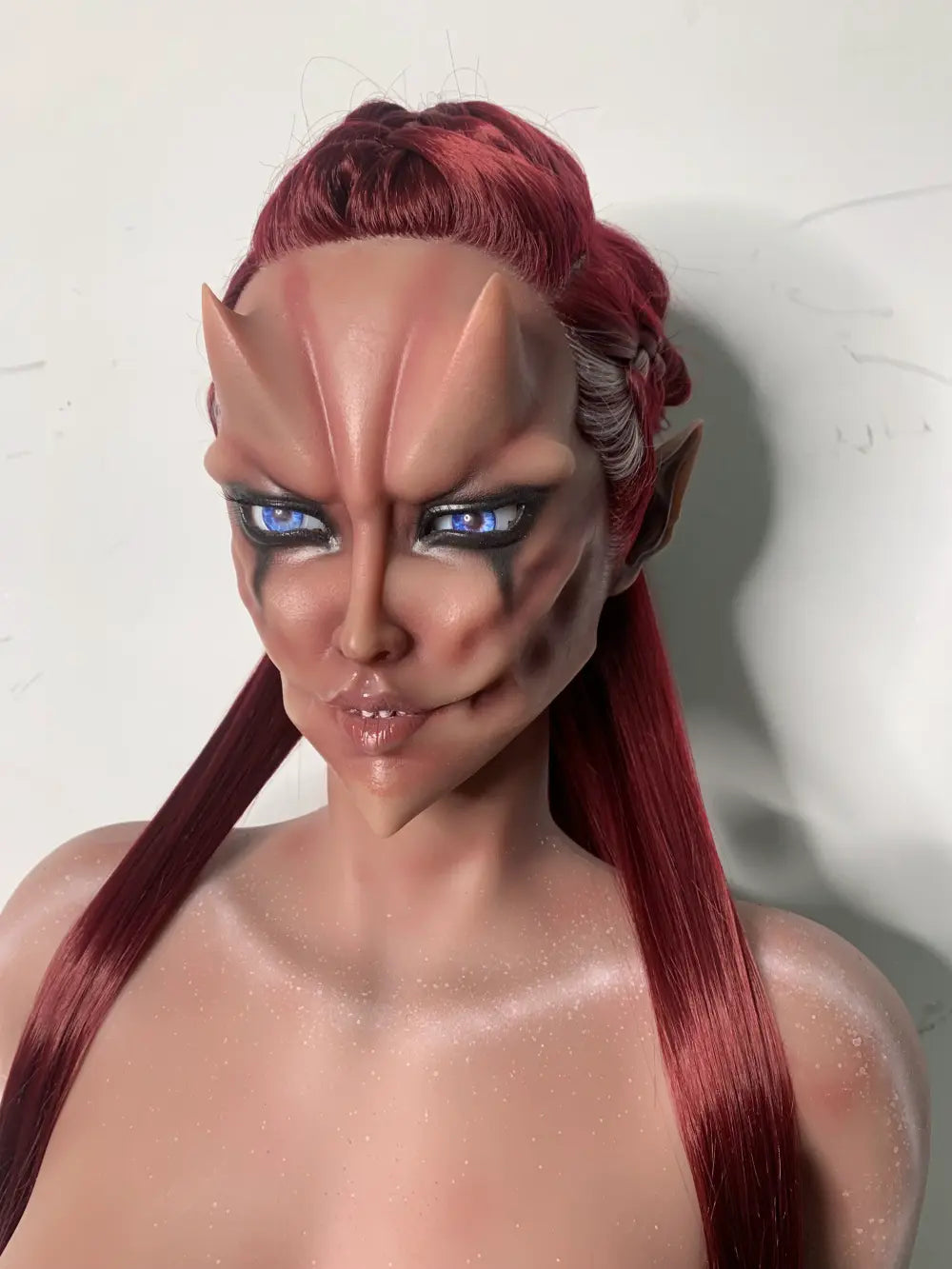 Front factory portrait of Veyra sex doll showing blue eyes, forehead ridges and red hair