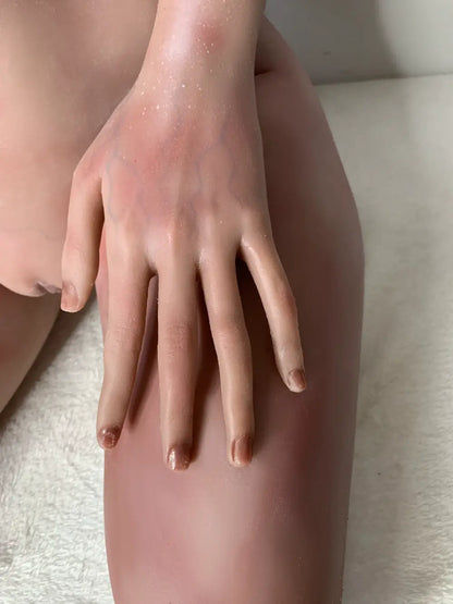 Factory detail photo of Vaelis sex doll's hand resting on the thigh, showing sculpted fingers and nails