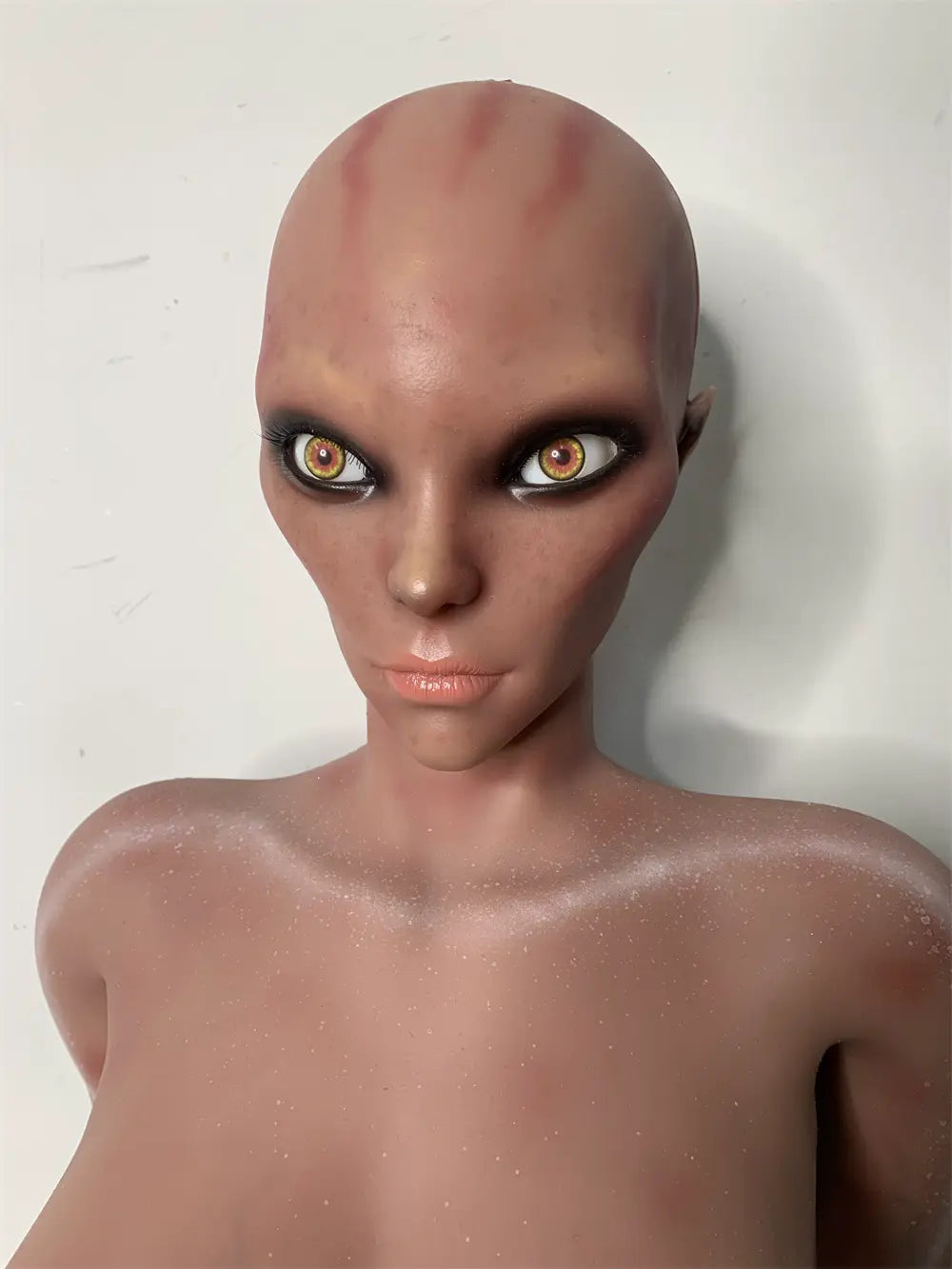 Factory close-up of Nyxie's alien face showing amber-colored eyes and forehead markings