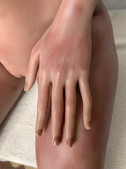 Factory detail photo of Nyxie sex doll's hand resting on the thigh, showing sculpted fingers and nails