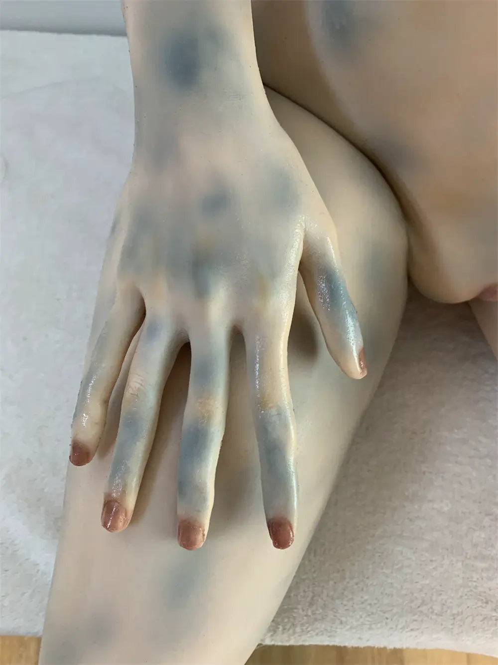 Factory detail photo of Morveth sex doll's hand resting on the thigh, showing sculpted fingers and nails