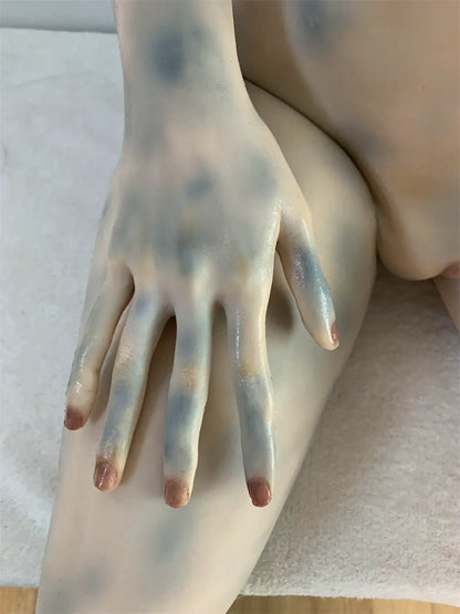 Factory detail photo of Morveth sex doll's hand resting on the thigh, showing sculpted fingers and nails