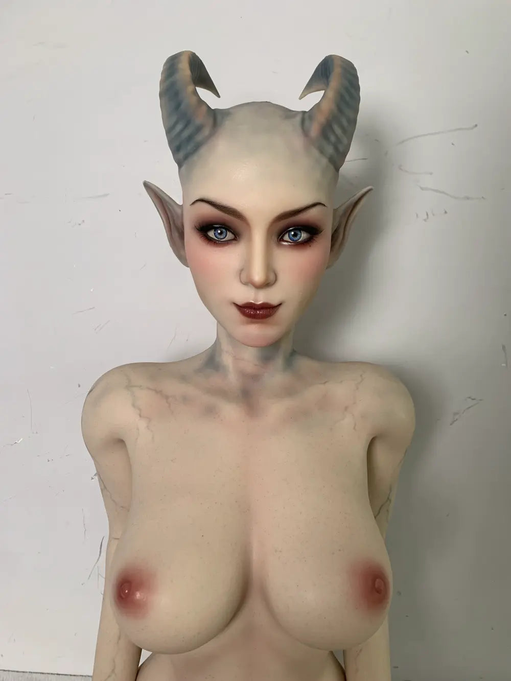 Front factory portrait of Veltris sex doll showing curved horns and pointed elf ears