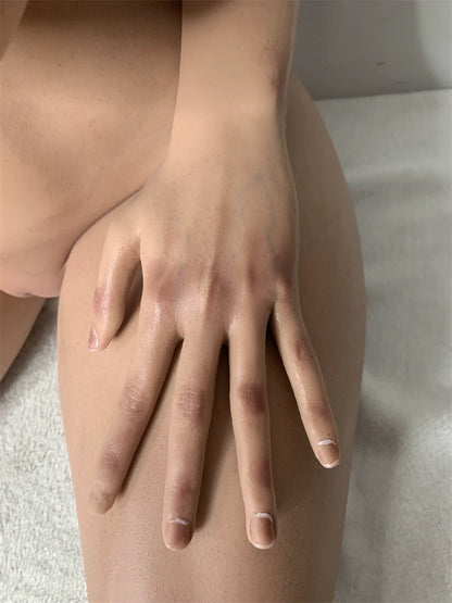 Factory detail photo of Nethrava sex doll's hand with dark fingernails resting on the thigh