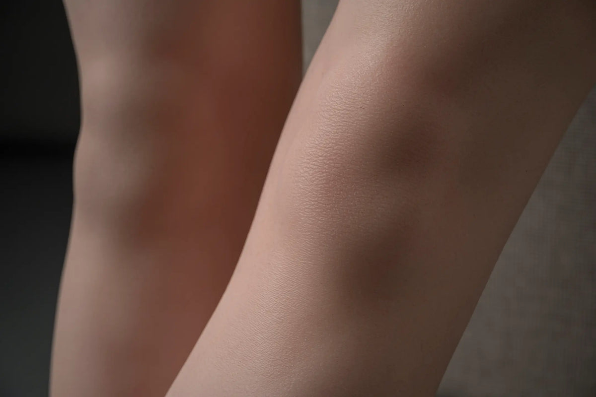 Close-up of Elowen doll's knees, showing subtle surface texture under soft studio lighting.