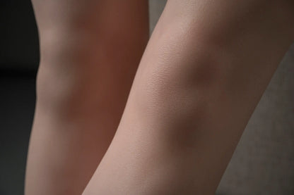 Close-up of Elowen doll's knees, showing subtle surface texture under soft studio lighting.